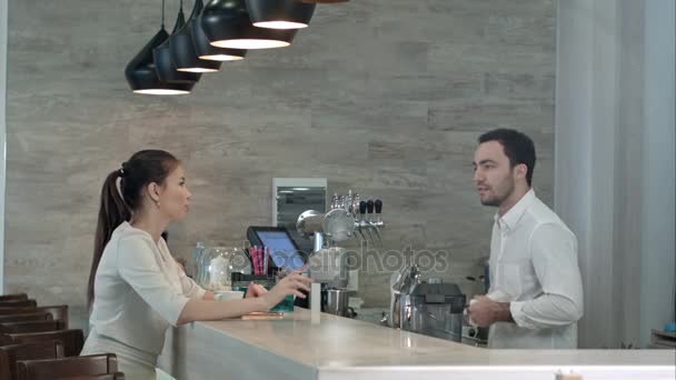 Uśmiechający się barista i młoda ładna kobieta rozmawia w kawiarni — Wideo stockowe