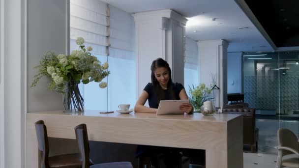 Улыбающаяся женщина с цифровым планшетом, сидя в кафе — стоковое видео