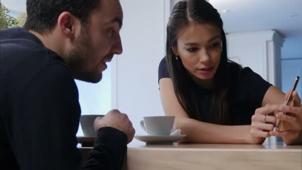 Mosolygó fiatal nő kávéház mutatja valami őt telefonon a férfi barátja — Stock videók