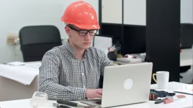 Genç mimar ofis içinde belgili tanımlık laptop üzerinde çalışıyor