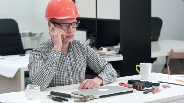 Joven arquitecto en casco con importante llamada telefónica — Vídeo de stock