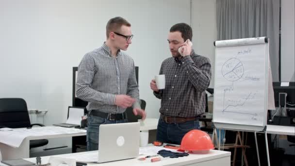 Dos arquitectos que tienen una llamada telefónica durante el descanso del café — Vídeos de Stock