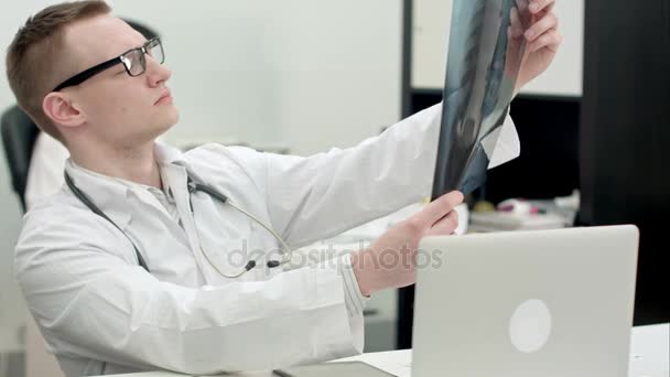 Молодий лікар-чоловік вивчає рентгенівські зображення — стокове відео