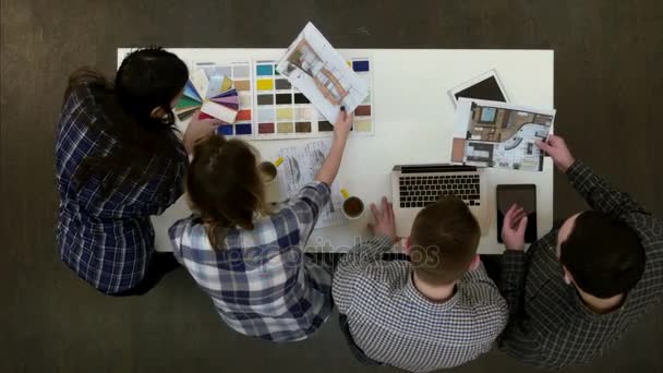 Два архітектори обговорюють компонування, а жінки-працівниці дивляться на кольорову палітру — стокове відео