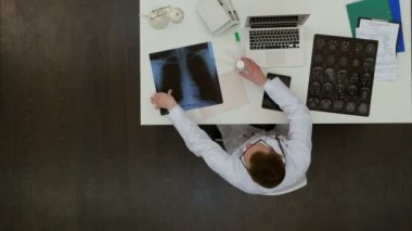 Genç erkek Doktor Röntgen görüntüleri onun masasında incelenmesi