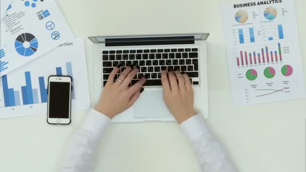 Mãos das mulheres digitando no laptop na mesa de escritório com gráfico de estatísticas — Vídeo de Stock