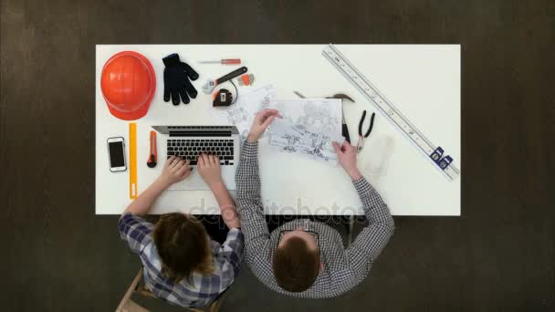 ノート パソコンでレポートを入力する女性の同僚間の設計図に取り組んでいる建築家 — ストック動画