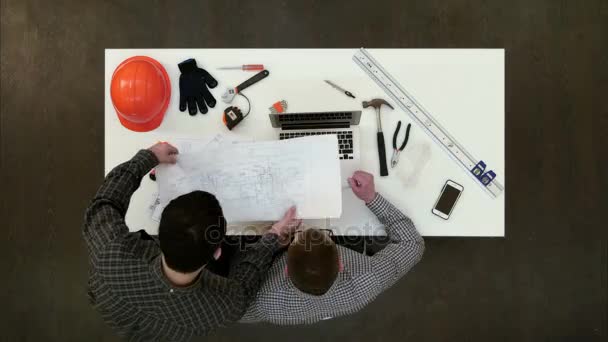 Dois arquitetos do sexo masculino discutindo desenhos e plantas — Vídeo de Stock