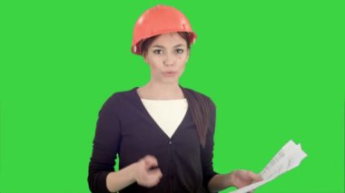 Kask bağırarak ve Chroma Key bir yeşil ekranda kamera içine parmak işaret belgelerle kızgın kadın mühendisi