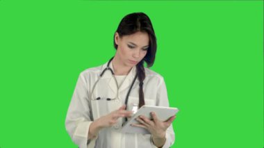 Tablet bilgisayar üstünde a yeşil perde, Chroma Key kullanarak stetoskop ile oldukça kadın doktor