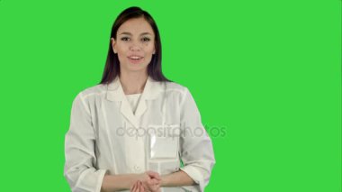Gülümseyen genç kadın Chroma anahtar yeşil ekran kameraya konuşurken laboratuvar önlüğü