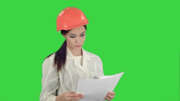 Vrouwelijke ingenieur in de helm lezen contract en knikken haar hoofd op een groen scherm, Chromakey — Stockvideo