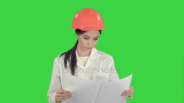 Mujer joven ingeniero con casco de seguridad examinando dibujos técnicos en una pantalla verde, Chroma Key — Vídeos de Stock