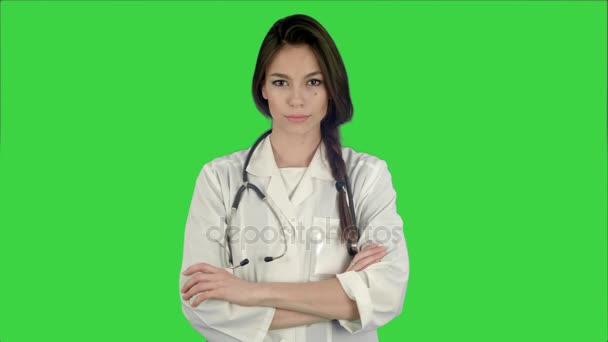 Attraktive junge Ärztin in weißem Mantel mit Stethoskop, die auf einem grünen Bildschirm in die Kamera blickt, Chroma-Schlüssel — Stockvideo