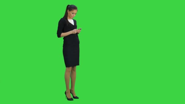 Genç işkadını Chroma anahtar yeşil ekran yürürken cep telefonu kontrol — Stok video