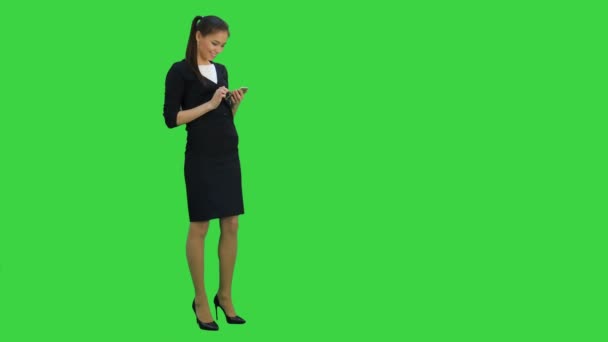 Vacker affärskvinna skrattar åt något roligt på sin smartphone på en grön skärm, Chroma Key — Stockvideo