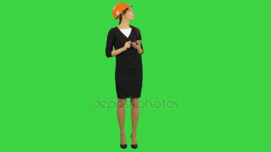 Kask kullanarak kadın mühendisi telefon fotoğraf inşaat yeşil ekran üzerinde Chroma Key almak için.
