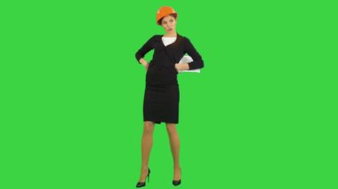 Kağıtları tutarak ve Chroma Key bir yeşil ekranda komik dansı yapan kask içinde kadın mühendis