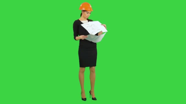 Junge weibliche Aufsichtsperson im Helm, die Baupläne hält und die Konstruktion auf einem grünen Bildschirm inspiziert, Chroma-Schlüssel — Stockvideo