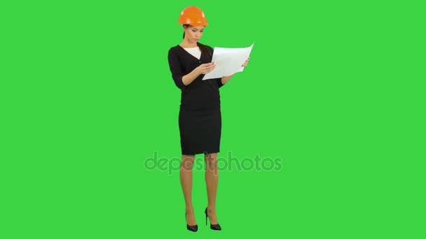 Νεαρός μηχανικός γυναίκα διαβάζοντας τεχνικά σχέδια και γέλιο σε μια πράσινη οθόνη, Chroma Key — Αρχείο Βίντεο