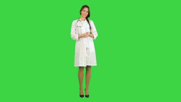 Hermosa joven doctora en bata de laboratorio con estetoscopio mirando a la cámara en una pantalla verde, Chroma Key — Vídeo de stock