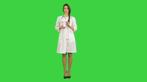 Sorridente medico femminile guardando la fotocamera e raccomandando vaso di pillole su uno schermo verde, Chroma Key — Video Stock