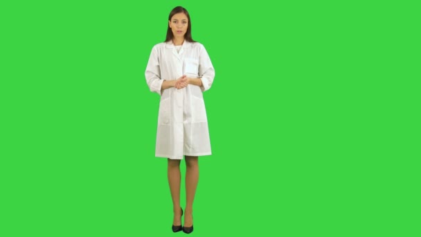 Serieuze jonge vrouw in lab uniforme praten met de camera op een groen scherm, Chromakey — Stockvideo