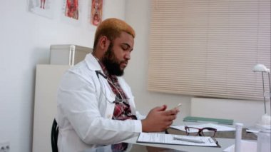 Veri yaptığı telefon kontrolü ve form doldurma Afro-Amerikan erkek doktor