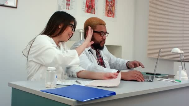 Zwei medizinische Mitarbeiter, die sich per Videoanruf mit dem Patienten beraten — Stockvideo
