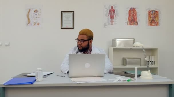 Afroamericano médico masculino trabajando en el ordenador portátil — Vídeo de stock