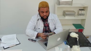 Genç afroamerican erkek doktor onun masasında para sayma