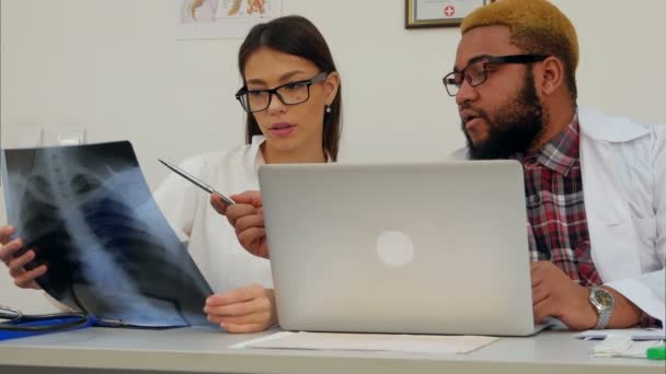 Dos doctores analizando la imagen de rayos X mientras usan la computadora — Vídeos de Stock