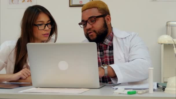 Чоловік лікар і його асистентка обговорюють щось над ноутбуком — стокове відео