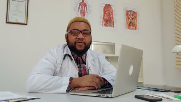 Afrikanischer amerikanischer Arzt spricht in seinem Büro vor der Kamera — Stockvideo
