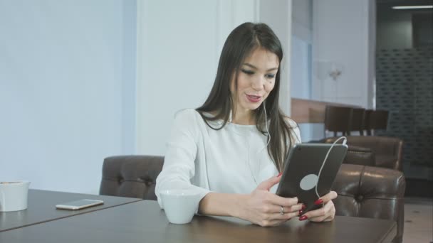 Femme attrayante dans les écouteurs ayant un appel vidéo via une tablette numérique — Video