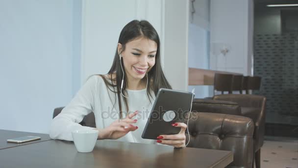 タブレット pc を使用して、カフェに座っている間はビデオ通話をする美しい若い女性 — ストック動画