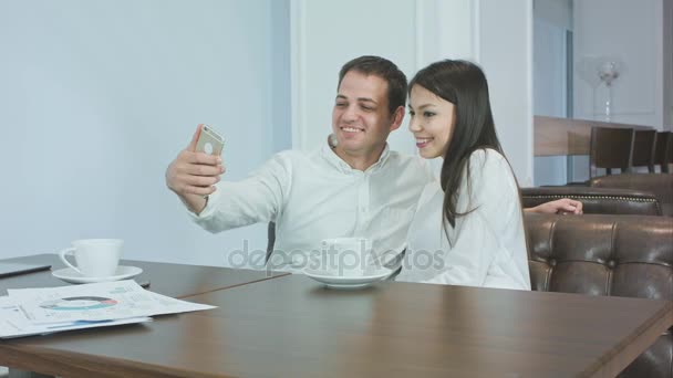 カフェで電話で面白い selfies を取ってビジネス同僚のカップル — ストック動画