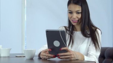 Gülümseyen kadın video seslenmek yolu ile dijital tablet bir kafede sahip kulaklık