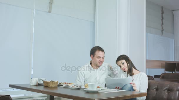 Молодая женщина разговаривает по телефону во время обеда и просит своего коллегу-мужчину о помощи — стоковое видео