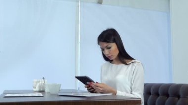 Bir kafede dijital tablet kullanan iş kadın konsantre