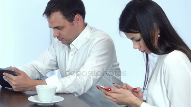 Twee jonge mensen in drukke werken met hun telefoon- en tablet café — Stockvideo
