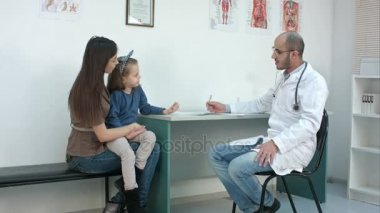 Onların sorunu açıklayan küçük kızıyla anne sırasında tıbbi formu doldurarak çocuk doktoru