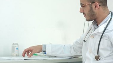Onun hasta tıbbi sonuçları gösterilen gözlüklü genç doktor