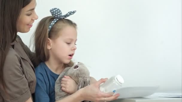 Lächelnde Mutter mit niedlichem Mädchen, das Tabletten und medizinische Form in der Hand hält — Stockvideo