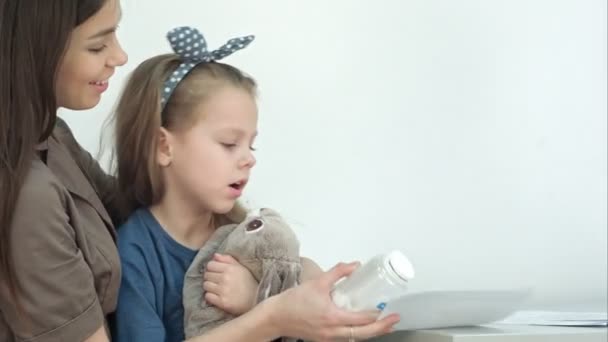 Sorrindo mãe com bonito menina segurando pílulas e forma médica — Vídeo de Stock