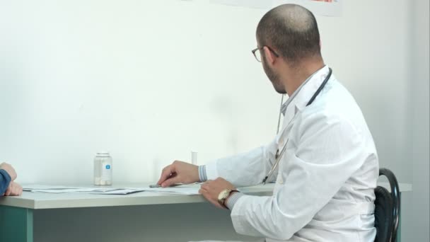 Smiling doctor giving little patient a lollipop after the exam — Stock Video