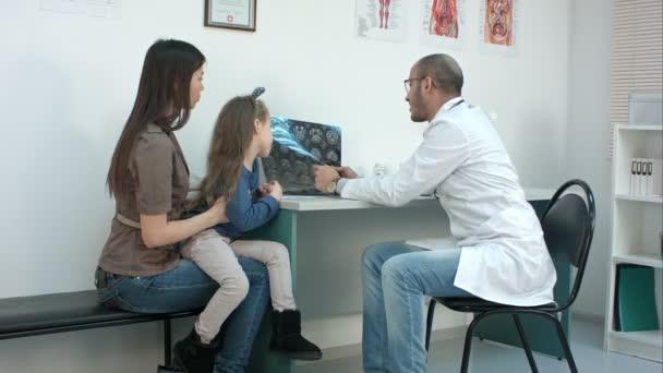 Доктор показывает рентгеновский снимок молодой матери с веселой дочерью — стоковое видео