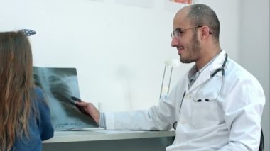 Küçük kız Xray görüntü ile oynarken gülümseyen erkek doktor tarafından düzenlenen