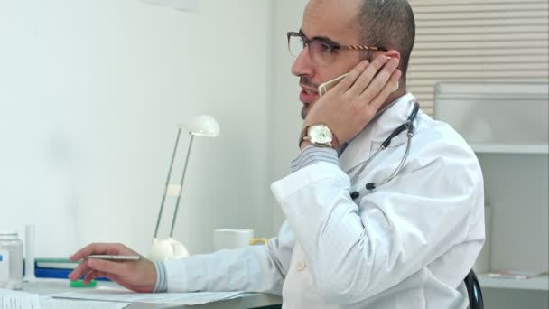 Arabe jeune médecin avoir une conversation téléphonique dans son bureau — Video