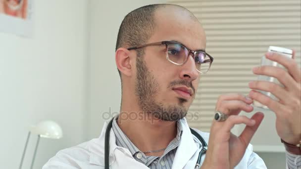 Male doctor attentively reading medicine label of a bottle of pills — Stock Video